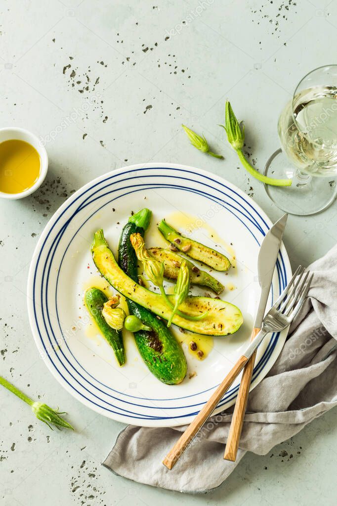 Grilled baby zucchini with flowers on the white plate - meal