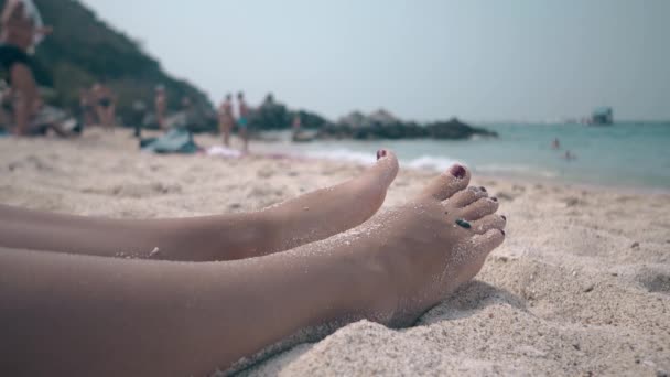 nohy a nohy pokryté suchým pískem leží na pobřeží