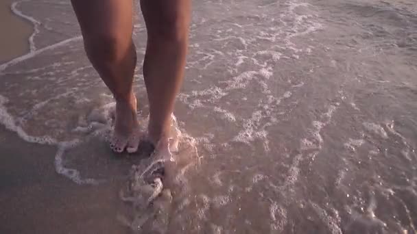 dívka bosých chodníků na písku a vlny pomalý pohyb