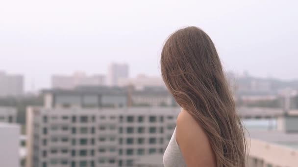 Girl with loose hair stands and looks at city slow motion — Stock Footage Girl with loose hair stands and looks at city slow motion Royalty Free Stock Video