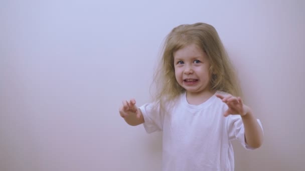 Pretty girl in t-shirt tries to scare at white wall in room — Stock Footage Pretty girl in t-shirt tries to scare at white wall in room Stock Footage