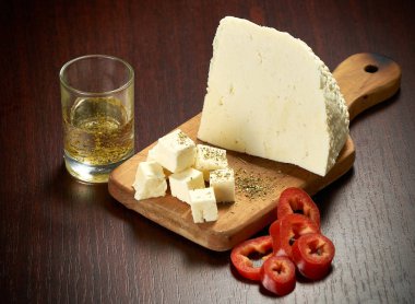 Hassas beyaz peynir ve bir ahşap tahta üzerinde kırmızı tatlı biber dilimleri. Koyu arka plan. Yakın çekim.