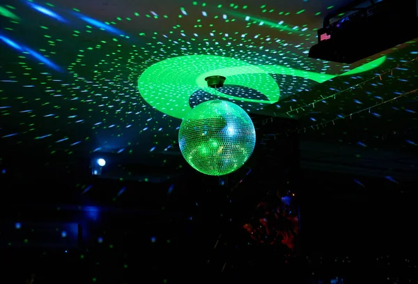Mirror disco ball at a music party. Reflected colored rays in a dark room.