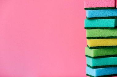 Pembe bir arka plan üzerinde katlanmış piramit temizlik için çok renkli süngerler.