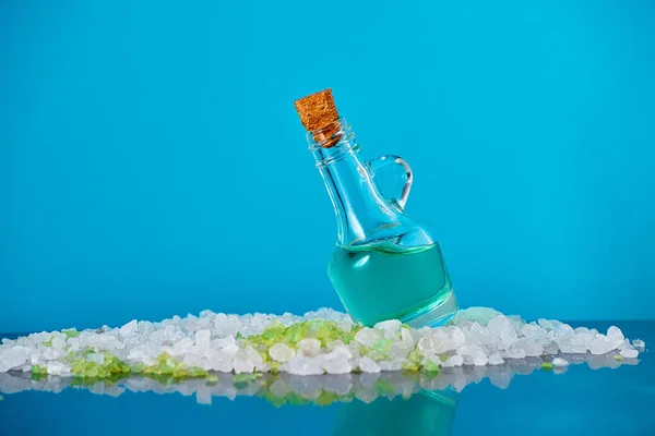 Glass bottle, sea salt on a blue background.