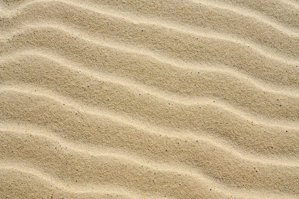 Textured background of beautiful wavy yellow sea sand. — Stock Photo, Image