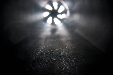 Dumandan geçen ışık ışınlarıyla aydınlatılmış karanlık bir alanda bir fan.