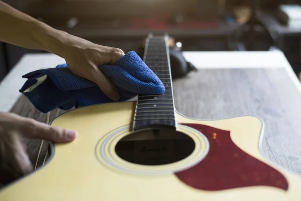 Guitar repairer is cleaning acoustic guitar