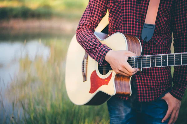 Music in nature, Man playing an acoustic guitar in meadow — Stock Fotó