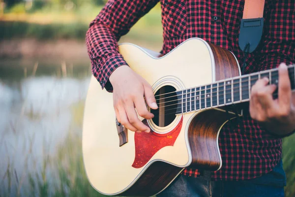 Music in nature, Man playing an acoustic guitar in meadow — Zdjęcie stockowe