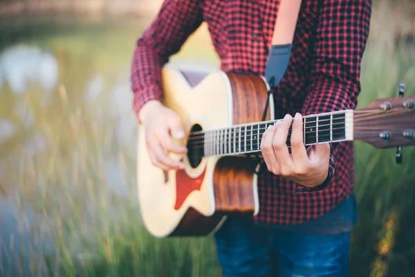 Музыка в природе, Человек играет на акустической гитаре в Meadow — стоковое фото