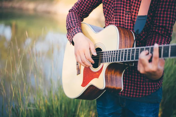 Music in nature, Man playing an acoustic guitar in meadow — Stock Fotó