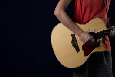 Karanlıkta akustik gitar çalan kırmızı tişörtlü müzisyen, boşluğu kopyala.