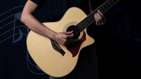 Musician with an acoustic guitar in the dark, Night photo with side lighting.