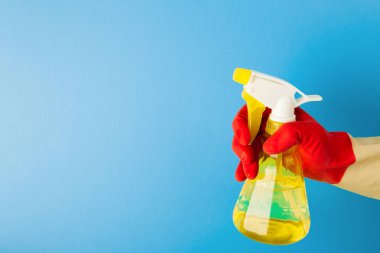 Kırmızı bir eldiven elinde tutan bir sprey sıvı temizlik