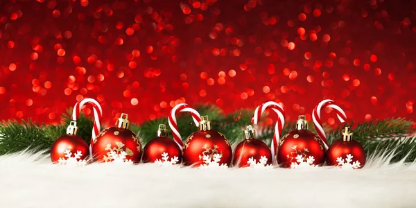 Bolas rojas de Navidad y decoraciones de caramelos sobre fondo rojo — Foto de Stock