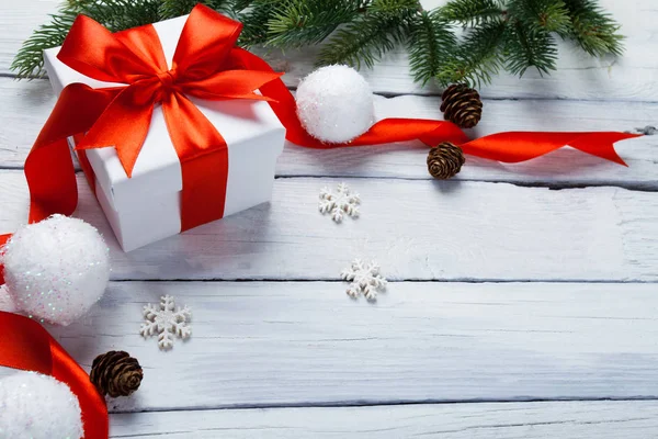 Weihnachts- oder Neujahrskarte. Geschenk, Baum- und Kugeldekoration auf weißem Holzgrund — Stockfoto