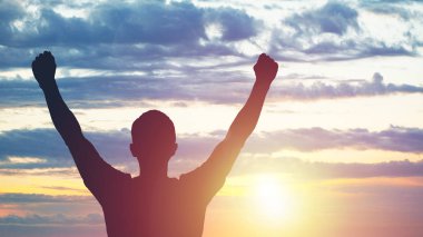 Gün batımında uzanmış ayakta genç adam. Parlak güneş ışıma ve gökyüzü