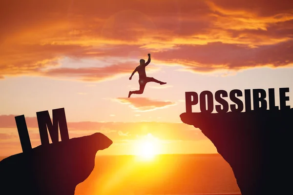 Man jumping over impossible or possible over cliff on sunset background — Stock Photo, Image