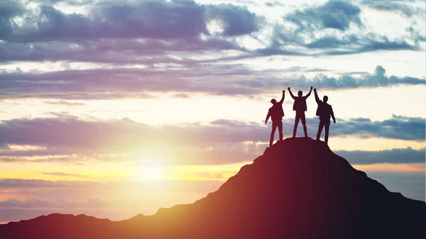 Silhouettes of happy three people on top of a mountain — Stock Photo, Image