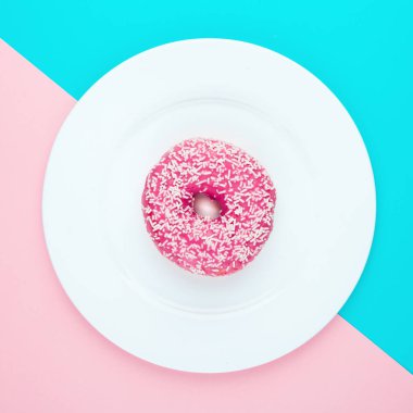 Renk arka plan üzerinde pembe sırlı çörek. Düz yatıyordu.