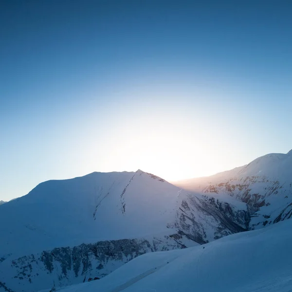 Montañas de nieve contra el sol. Fondo de invierno — Foto de Stock