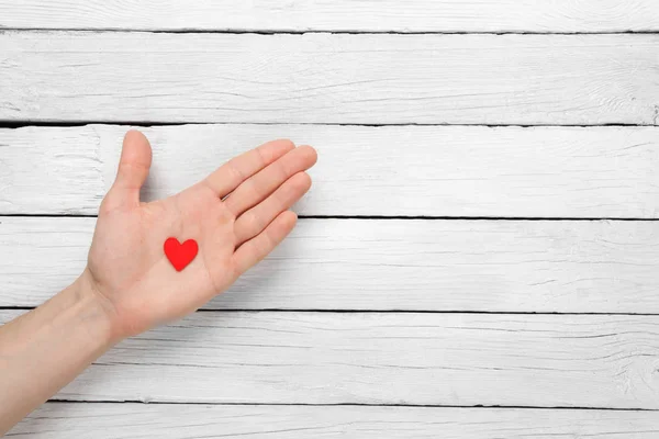 Coração na mão sobre um fundo de madeira — Fotografia de Stock