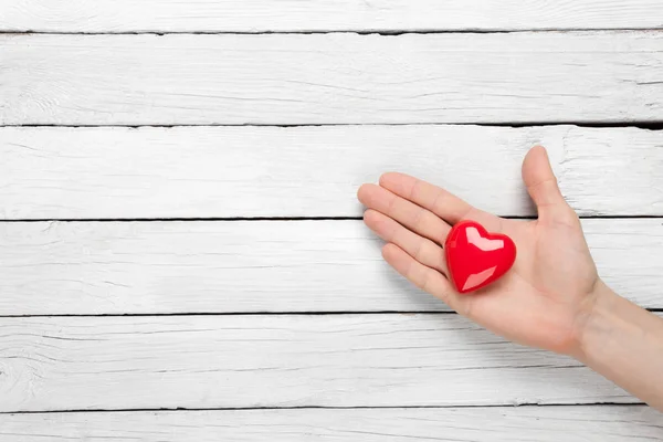 Coração na mão sobre um fundo de madeira — Fotografia de Stock
