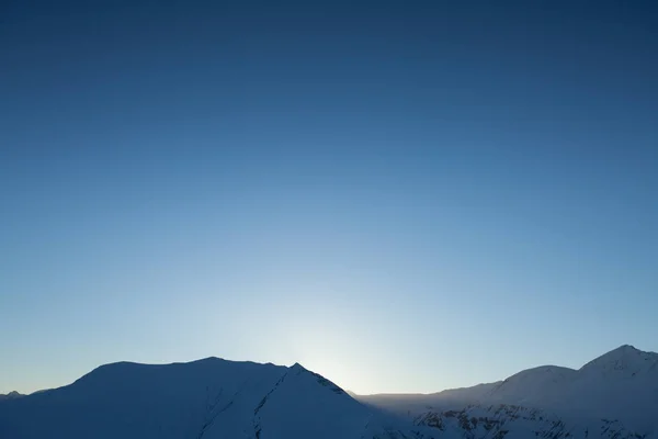 Montañas de nieve contra el sol. Fondo de invierno — Foto de Stock