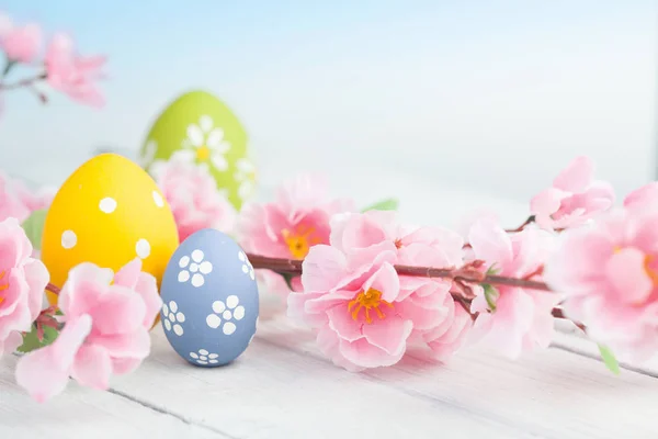 Ostereier und rosa Blumen Dekoration auf blauem Hintergrund — Stockfoto