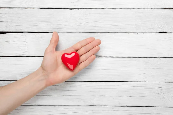 Heart in the hand on a wooden background — Stock Photo, Image