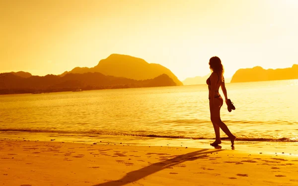 Девочка, гуляющая на пляже на закате — стоковое фото