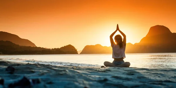 Genç kız günbatımı zaman yoga yaparken silüeti — Stok fotoğraf