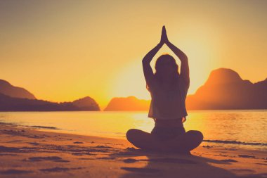 gün batımında arka planda kayalar ile okyanus tarafından meditasyon kadın