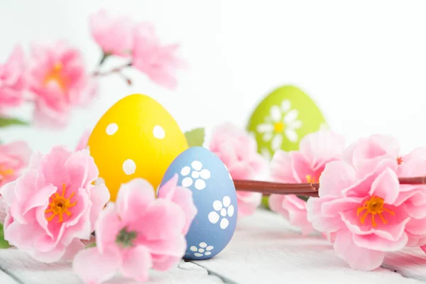 Ostereier und rosa Blumen Dekoration auf blauem Hintergrund — Stockfoto