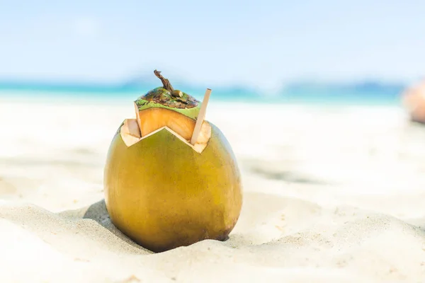 Fresh young coconut lying on the sand beach background with straw ready for drink. — Stock Photo, Image