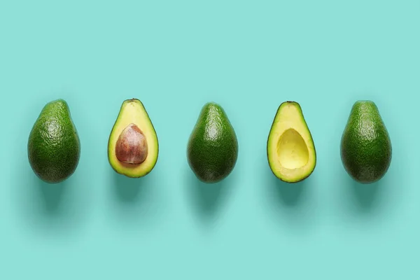 Reihe frischer Löcher und Hälften von Bio-Avocado mit Kernen in der Mitte auf blauem Backgrond. Ansicht von oben — Stockfoto