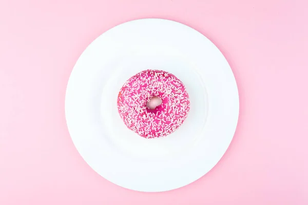 Rosafarbener runder Donut auf hellrosa Hintergrund — Stockfoto