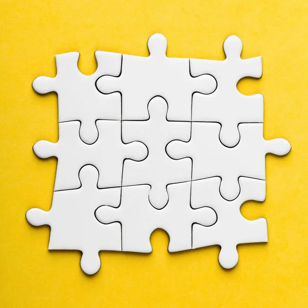 З'єднані порожні шматочки головоломки на жовтому тлі . — стокове фото