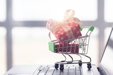 Online alışveriş konsepti. Alışveriş sepeti, küçük hediye kutuları, masanın üzerinde dizüstü bilgisayar
