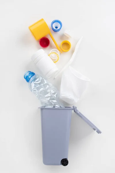 Papelera con residuos de plástico sobre un fondo gris. Concepto de reciclaje — Foto de Stock