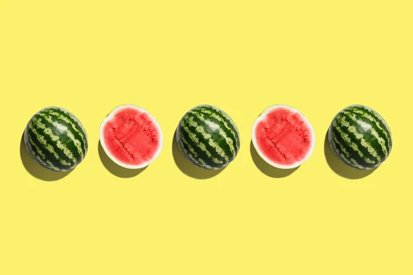 Row of fresh watermelon in center on yellow backgrond. — Stock Photo, Image