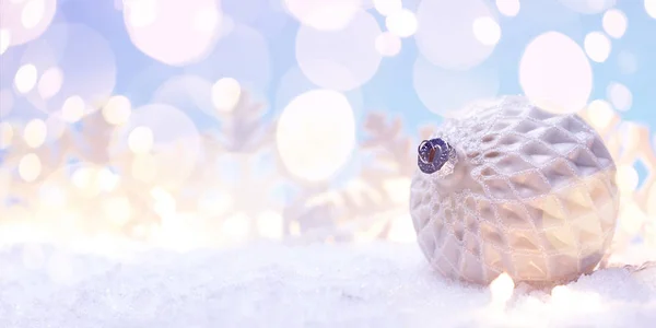 Bola branca de Natal com flocos de neve na neve . — Fotografia de Stock