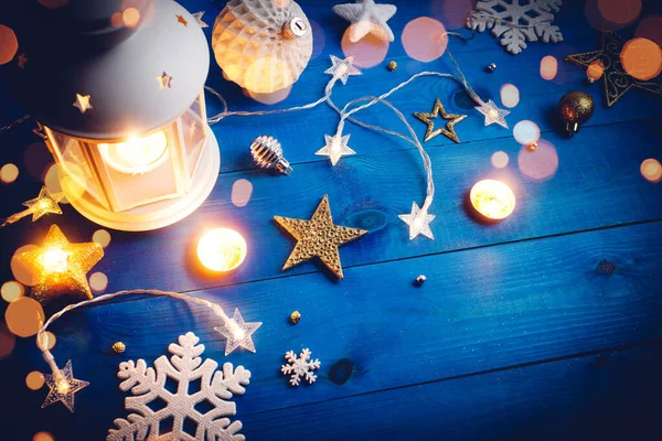 Горящий фонарь с рождественским декором на синем деревянном фоне. — стоковое фото