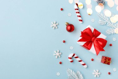 Mavi arka planda Noel süslemeleri olan kırmızı hediye kutusu