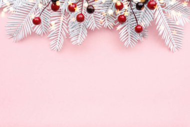 Noel sınırında köknar dalları, rowan ve pastel pembe arka planda altın ışıklar
