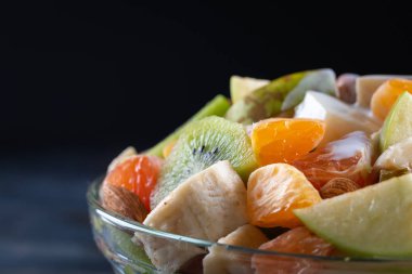 Tahta arka planda bir kase sağlıklı taze meyve salatası. Üst görünüm.