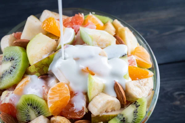 Tahta arka planda bir kase sağlıklı taze meyve salatası. Üst görünüm.