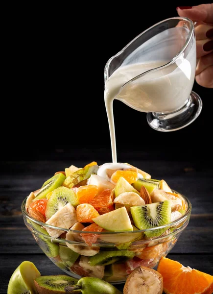 Tahta arka planda bir kase sağlıklı taze meyve salatası. Üst görünüm.