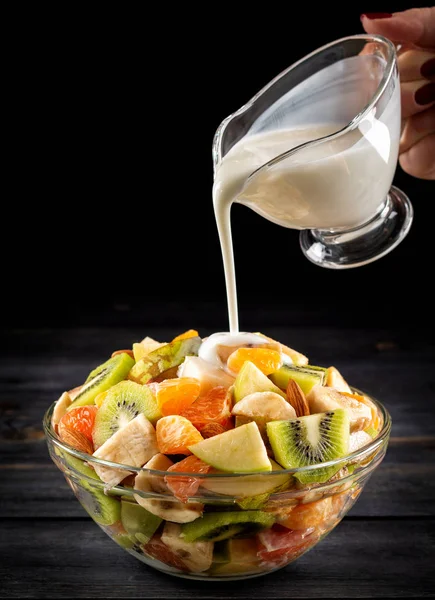 Tahta arka planda bir kase sağlıklı taze meyve salatası. Üst görünüm.